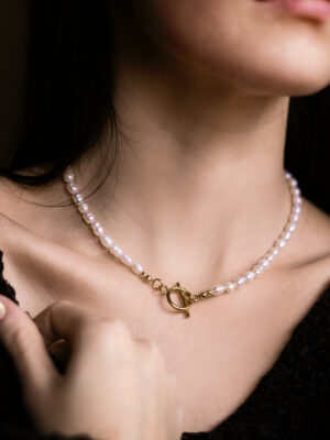 Kobieta w ręcznie wykonanym naszyjniku z pereł naturalnych ze złotym zapięciem