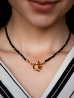 Modelka w ręcznie robionym naszyjniku z czarnych turmalinów ze złotym zapięciem w postaci toggle