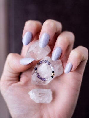 Pierścionek z ametystów i czarnych turmalinów ułożony na kobiecej dłoni