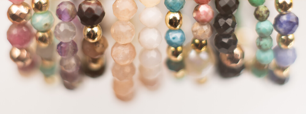 Kolorowe pierścionki z kamieni naturalnych zawieszone na złotym ekspozytorze